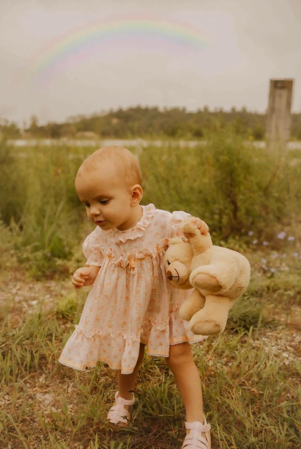 Little girl sitting on a teddy bear wearing vintage clothing from Dear Elliemae